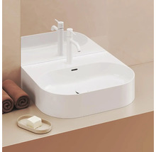 Moderná kúpeľňa s bielym umývadlom na dosku, batériou a uterákmi.