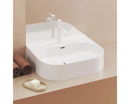 Moderná kúpeľňa s bielym umývadlom na dosku, batériou a uterákmi.