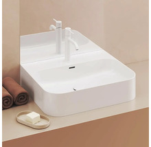 Biele umývadlo na dosku s batériou, uteráky a mydlo na umývadlovej skrinke