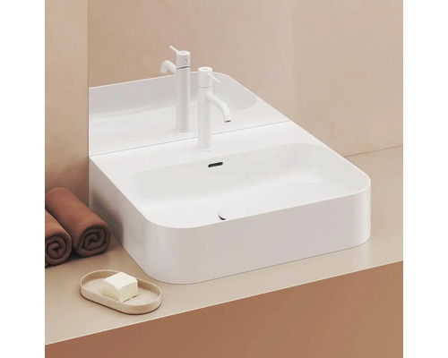 Biele umývadlo na dosku s batériou, uteráky a mydlo na umývadlovej skrinke