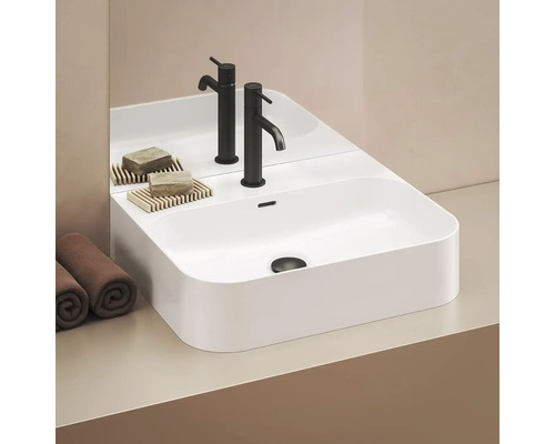 Moderné umývadlo s batériami, mydlom a uterákmi v kúpeľni.