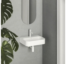 Biele umývadlo s batériou a zrkadlom vo svetlej kúpeľni.