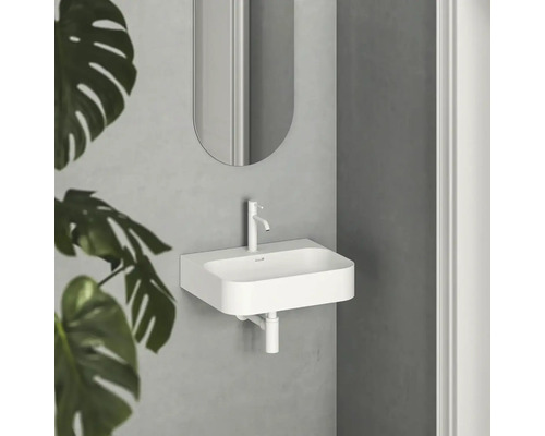 Biele umývadlo s batériou a zrkadlom vo svetlej kúpeľni.