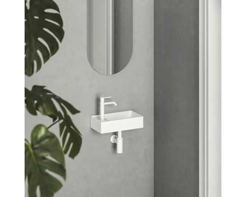 Malý umývadlový priestor s bielym umývadlom, batériou a zrkadlom