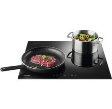 Indukčná varná doska so steakom na panvici a hrncom zeleniny