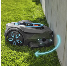 Robotická kosačka na trávu kosí trávu pozdĺž steny