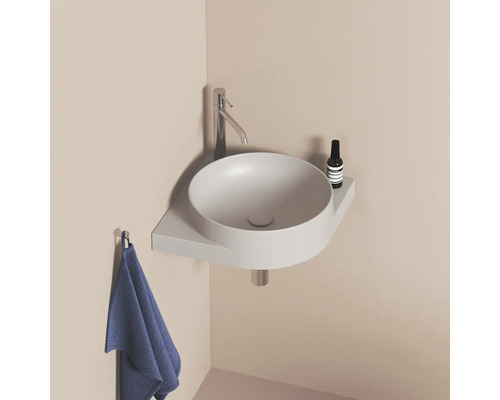 Okrúhle umývadlo s batériou, odkladacou plochou a uterákom v kúpeľni