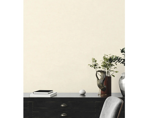 Dekoratívny interiér s komodou, knihami, rastlinami a skulptúrami pred stenou