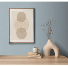 Dekoratívne zátišie s umeleckou tlačou v ráme, knihami, šálkou a vázou na stole