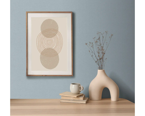 Dekoratívne zátišie s umeleckou tlačou v ráme, knihami, šálkou a vázou na stole