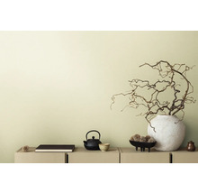 Dekoratívna scéna s čajovou kanvicou, knihou a vetvami vo váze na príborníku