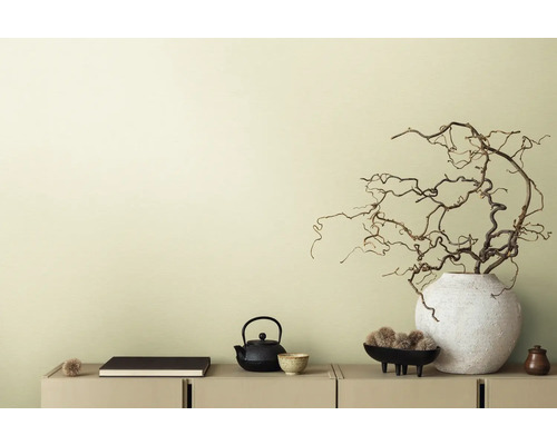 Dekoratívna scéna s čajovou kanvicou, knihou a vetvami vo váze na príborníku