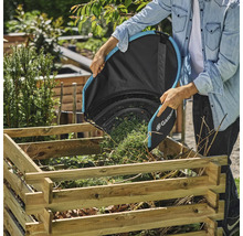 Osoba vysýpa vrece na lístie Gardena do dreveného uhoľného koša v záhrade.