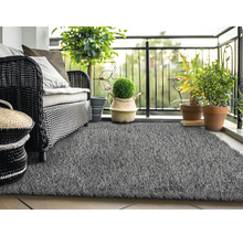 Balkónová scéna s ratanovou pohovkou, rastlinami a sivým umelým trávnikom