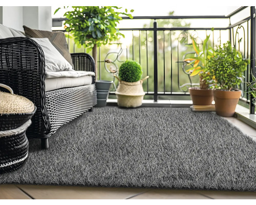 Balkónová scéna s ratanovou pohovkou, rastlinami a sivým umelým trávnikom