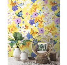 Dekoratívny interiér so žltou tapetou, zdobenou kvetmi, motýľmi a vtákmi, doplnený o prútené kreslo a izbové rastliny