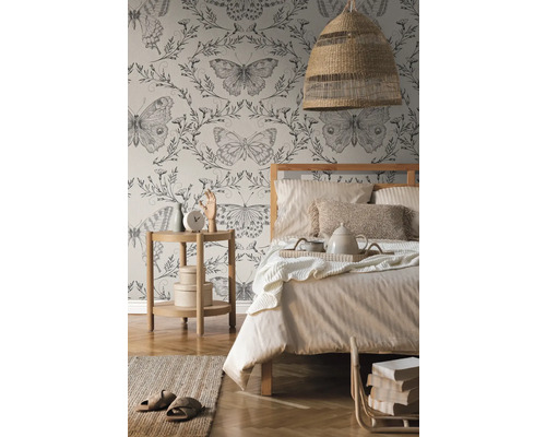 Spálňa s posteľou, nočným stolíkom, lampou a tapetou s motýľovým vzorom