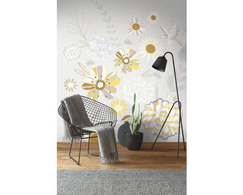 Dekoratívna nástenná dekorácia s kvetinovým vzorom, kreslo, stojacia lampa a kaktus v kvetináči.