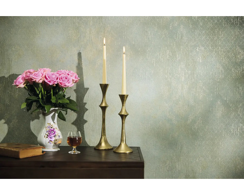 Dekoratívne aranžmán s ružami, sviečkami a starožitnými prvkami na stole pred vzorovanou stenou