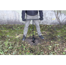 Osoba používa zemný vrták na vyvŕtanie diery do zeme.