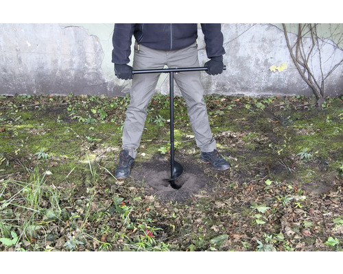 Osoba používa zemný vrták na vyvŕtanie diery do zeme.