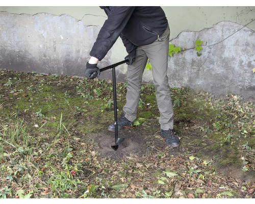 Osoba vŕta dieru do zeme pomocou zemného vrtáka.