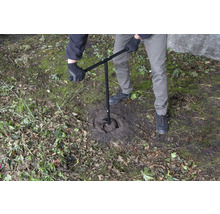 Osoba používa zemný vrták na vyvŕtanie diery do zeme.