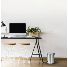 Scéna so stolom, stoličkami a kovovým odpadkovým košom s pedálom