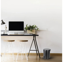 Pracovňa so stolom, stoličkami a okrúhlym odpadkovým košom.