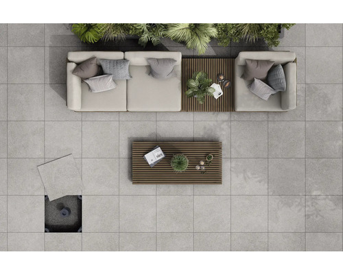 Pohľad zhora na terasu so svetlosivými terasovými doskami, sedacím nábytkom a drevenými stolmi