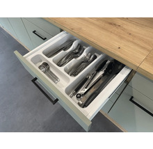 Otvorená kuchynská zásuvka s vložkou na príbory a rôznymi kusmi príborov.