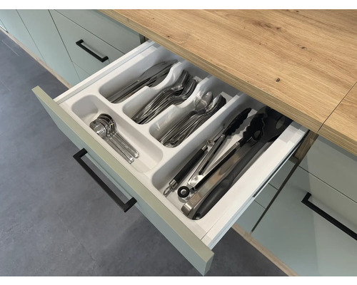 Otvorená kuchynská zásuvka s vložkou na príbory a rôznymi kusmi príborov.