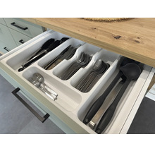 Otvorená zásuvka s vložkou na príbory a rôznym kuchynským náčiním ako kliešte, nože, vidličky, lyžice a naberačky.