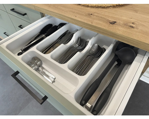 Otvorená zásuvka s vložkou na príbory a rôznym kuchynským náčiním ako kliešte, nože, vidličky, lyžice a naberačky.