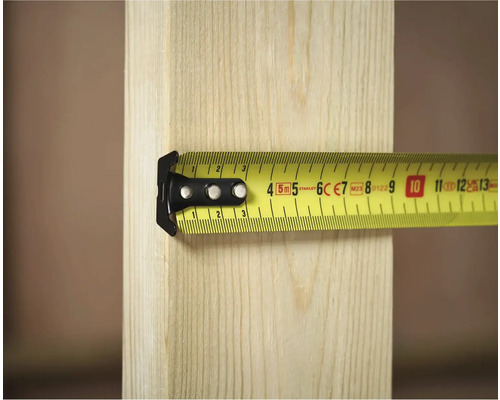 Žltý zvinovací meter Stanley meria kus dreva.