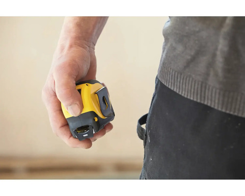 Ruka drží žltý a čierny zvinovací meter.