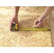 Osoba meria kus dreva pomocou zvinovacieho metra Stanley Fatmax s dĺžkou 5 metrov a označuje ho ceruzkou.