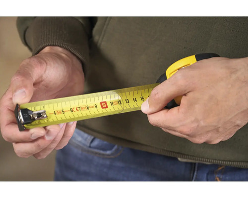 Osoba drží v ruke žltý zvinovací meter.