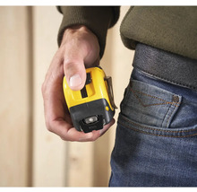 Osoba drží žltý zvinovací meter s klipom na opasok.
