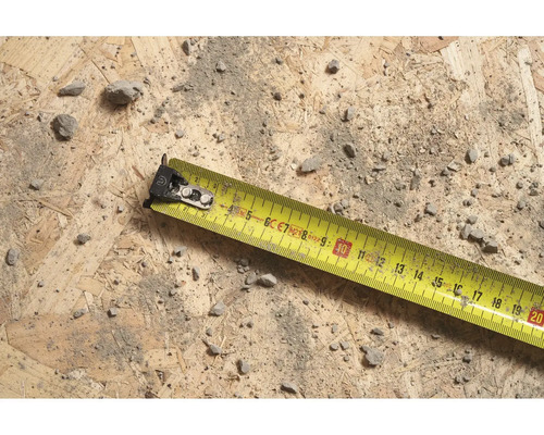 Žltý zvinovací meter na drevenom povrchu so špinou