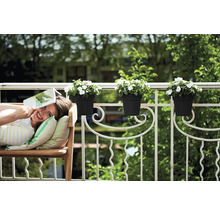 Žena relaxuje s knihou na lavičke na balkóne s kvetináčmi