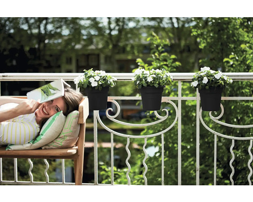 Žena relaxuje s knihou na lavičke na balkóne s kvetináčmi