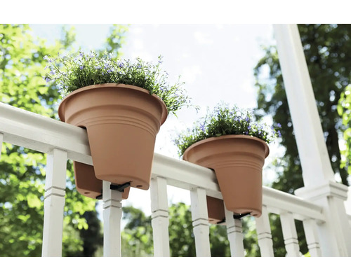 Dva kvetináče visia na zábradlí s kvetmi.