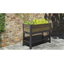 Vyvýšený záhon s úložným priestorom a rastlinami pred tehlovou stenou