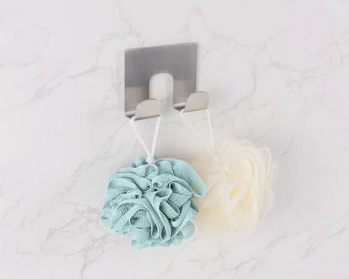 Pohľad zhora na nerezový háčik na uteráky s kúpeľovými hubkami na mramorovej stene