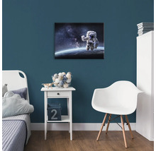 Detská izba s obrázkom astronauta na stene, nočný stolík a stolička.