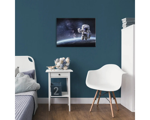 Detská izba s obrázkom astronauta na stene, nočný stolík a stolička.