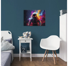 Dekoratívna detská izba s obrázkom astronauta na modrej stene nad nočným stolíkom.