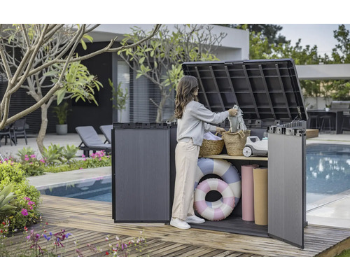 Snímka ženy používajúcej vonkajší úložný box na drevenej terase pri bazéne na ukladanie vecí