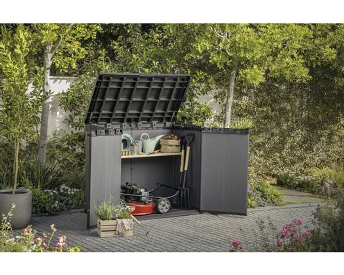 Záhradná skriňa s otvorenými dverami a vyklopeným vekom, vyplnená záhradným náradím a kosačkou na trávu